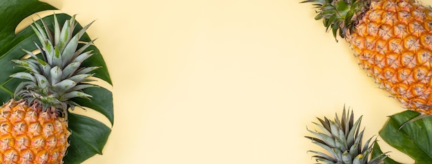 Фото Красивый ананас на тропической пальме монстера листья изолированы на ярком пастельно-желтом фоне верхний вид плоский лежит над головой над летними фруктами