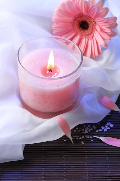 Beautiful pink candle with flower on bamboo mat