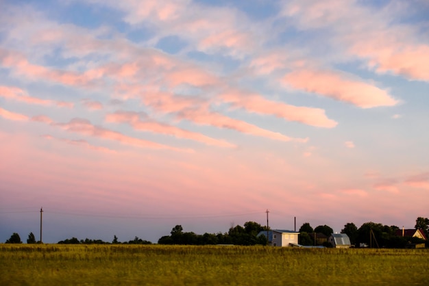 Belle nuvole rosa nel cielo blu durante il tramonto sui cottage di campagna