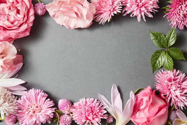 Beautiful pink flowers frame on black surface