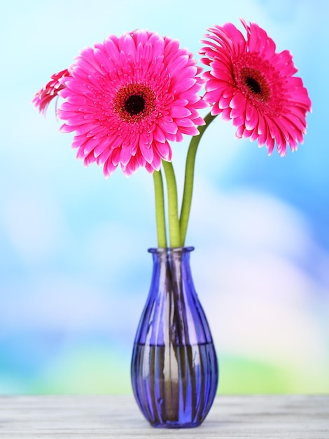 Beautiful pink gerbera flowers in vase on wooden table