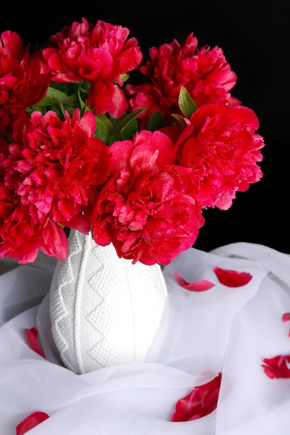 Beautiful pink peonies in vase, on dark