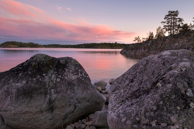 Beautiful pink sunset on Lake Ladoga in Karelia, Russia in the Ladoga Skerries national park in summer. Natural landscape with water rocks, stone islands.