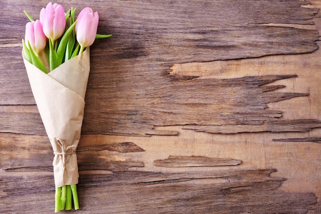 Beautiful pink tulips in paper on wooden background