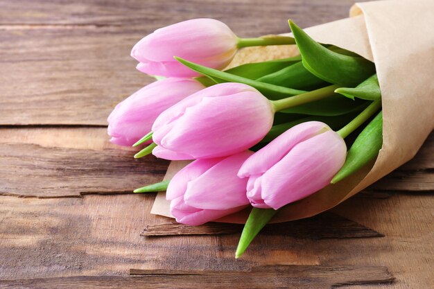 Beautiful pink tulips in paper on wooden background