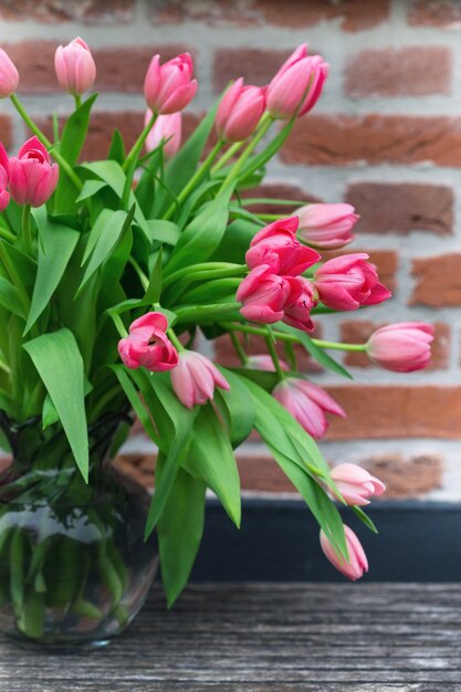 Beautiful pink tulips in a vase against a brick wall background