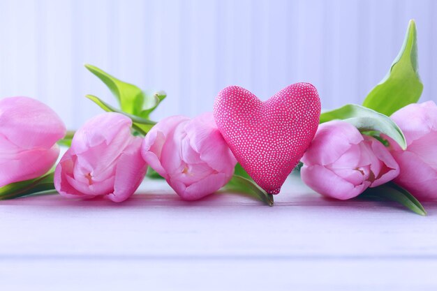 Beautiful pink tulips with decorative heart on wooden background