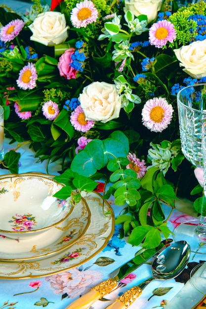 豪華なテーブルに立つ美しい皿と新鮮な完璧な色とりどりの花