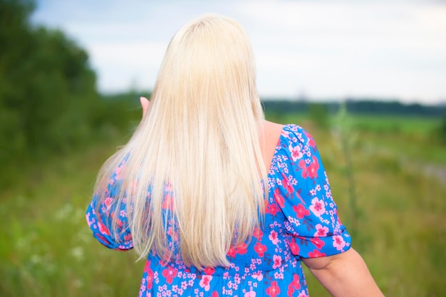 A beautiful plus size girl with white hair in a summer flower dress stands