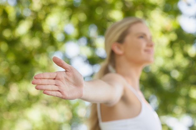 Beautiful ponytailed woman doing yoga spreading her arms