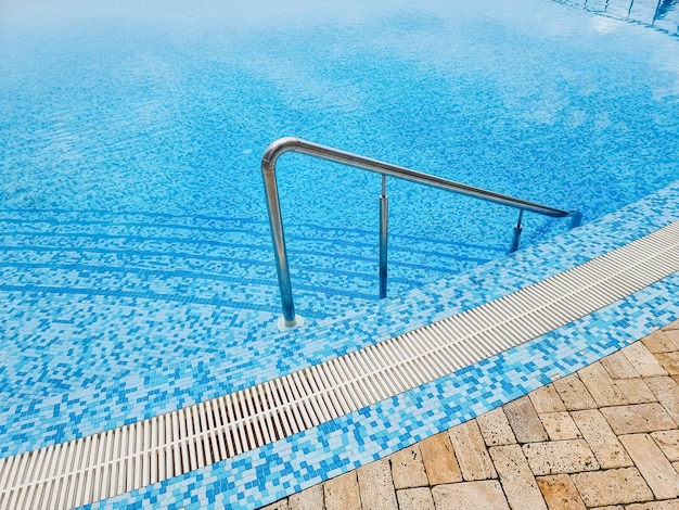 Beautiful pool with a metal handrails descent and blue water at sunset swimming and summer rest conceptpool with a metal handrail safety for water sports
