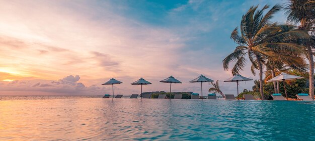 Beautiful poolside and sunset sky. Luxurious tropical beach landscape, deck chairs and loungers