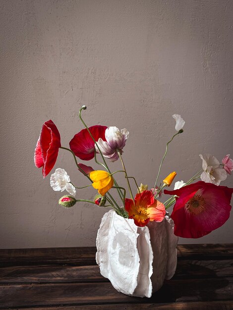不機嫌な素朴な背景に日光の下で花瓶に美しいケシ スタイリッシュな花の静物画の芸術的組成花の垂直壁紙