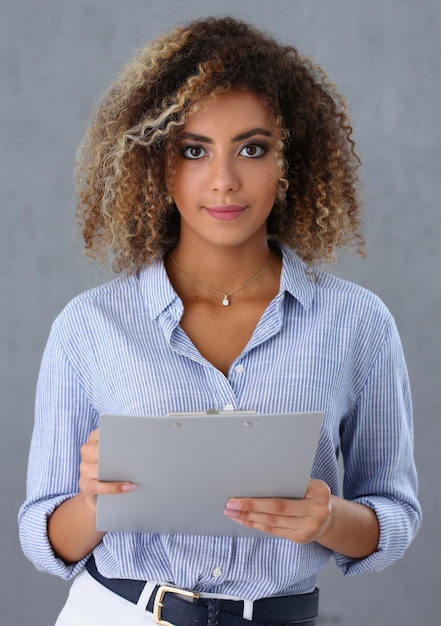 Beautiful portrait of black hispanic woman holding clipboard with business documents