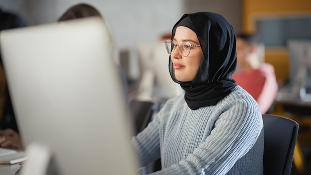 Beautiful Portrait of a Female Muslim Student in Hijab Studying in University She Works on Desktop Computer in College Applying Her Knowledge to Acquire Academic Skills in High School Classroom