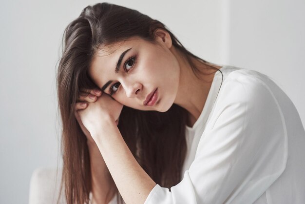 Photo beautiful portrait of gorgeous woman young brunette in the room with white walls and daylight that comes from the window