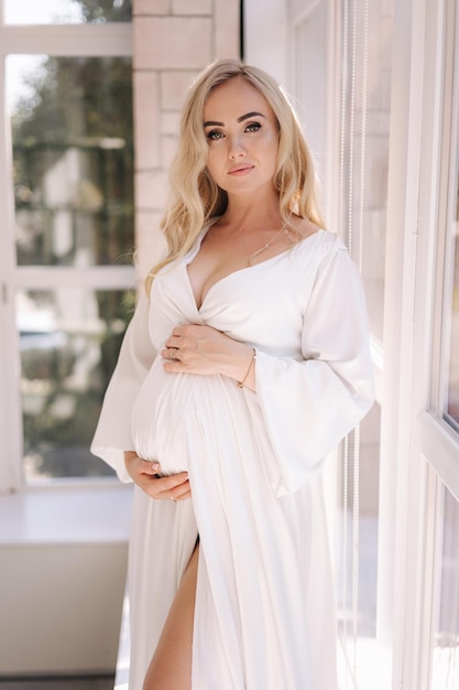 Beautiful portrait of pregnant woman in white dress concept of perfect pregnancy woman put her hand