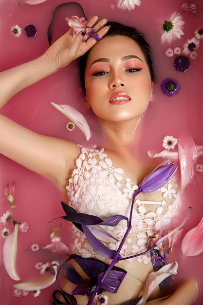 Красивый портрет женщины с цветами и лепестками в розовой воде Косметика для лица, увлажняющая кожу