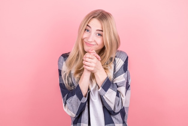 Beautiful positive friendly-looking young european girl with lovely sincere smile feeling thankful and grateful, showing her heart filled with love and gratitude holding hands on her breast