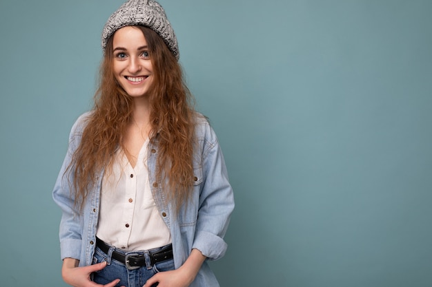 Beautiful positive happy young dark blonde woman isolated over colourful background wall wearing casual stylish clothes feeling sincere emotions looking at camera. Copy space