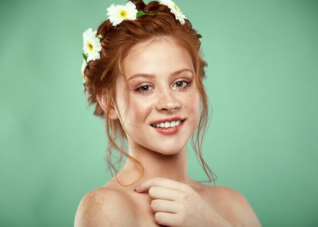 Beautiful positive redheaded girl with a chamomile crown on her head