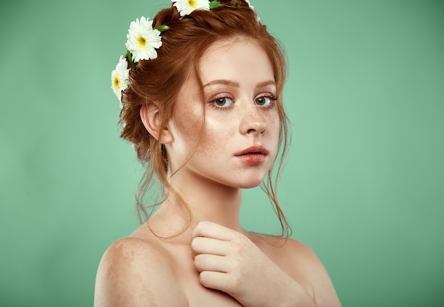 Beautiful positive redheaded girl with a chamomile crown on her head