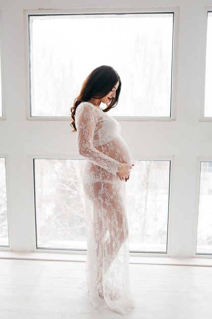 Beautiful pregnant girl in a white dress in the interior