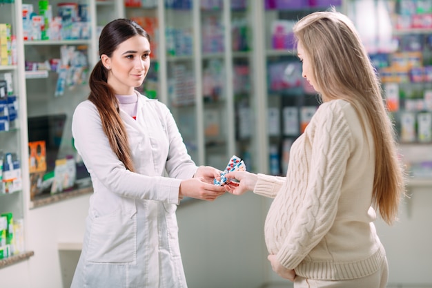 A beautiful pregnant woman consults at a pharmacy.