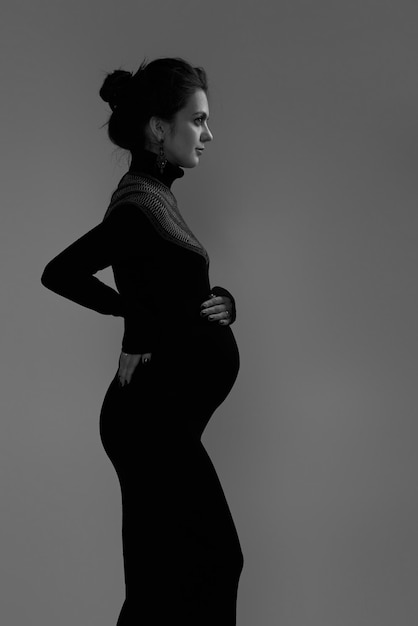 Beautiful pregnant woman in dress holding her belly