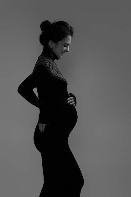 Beautiful pregnant woman in dress holding her belly