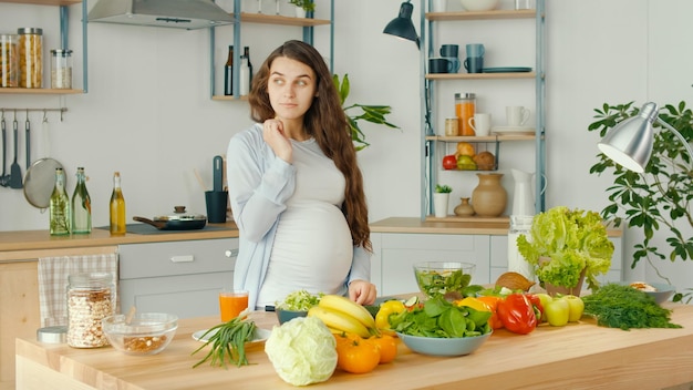 Beautiful Pregnant Woman Happily Preparing a Vegetable Salad The Concept Of Diet