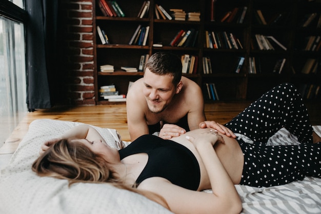 Beautiful pregnant woman and her handsome husband are hugging and smiling while spending time together