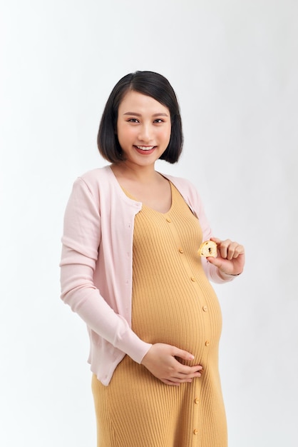 Beautiful pregnant woman holds tasty grains bread in her kitchen