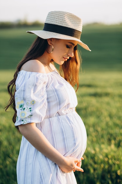 日没の春自然フィールドで美しい妊娠中の女性