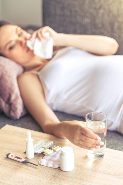 Beautiful pregnant woman is having cold, wiping her nose.