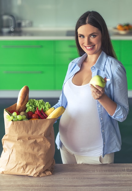 Beautiful pregnant woman is holding an apple.