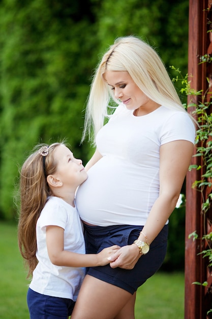 Photo beautiful pregnant woman and little daughter.