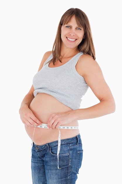 아름 다운 임신 한 여자 서있는 동안 그녀의 배꼽을 측정