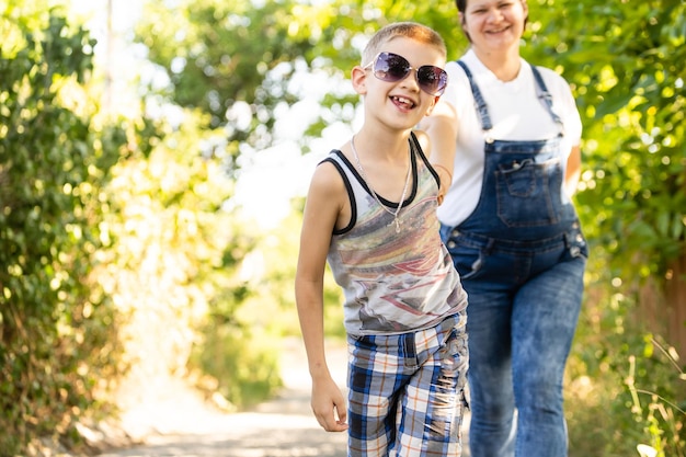 Beautiful pregnant woman and mother with her cute child toddler son have fun in summer park.