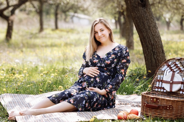 Фото Красивая беременная женщина на пикнике в цветущем весеннем саду.