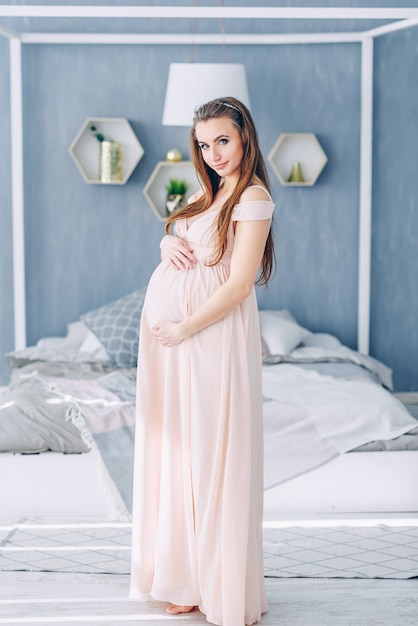 임신 배꼽을 잡고 핑크 드레스에 아름 다운 임신 한 여자