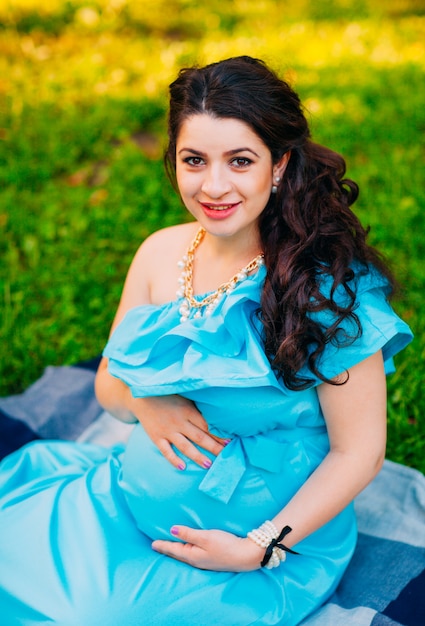 Beautiful pregnant woman relaxing outside in the park