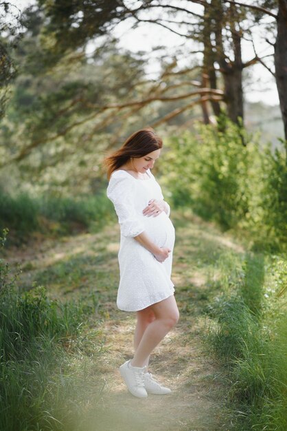 Beautiful pregnant woman relaxing outside in the park