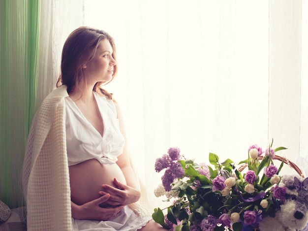 窓の近くに座っている美しい妊婦