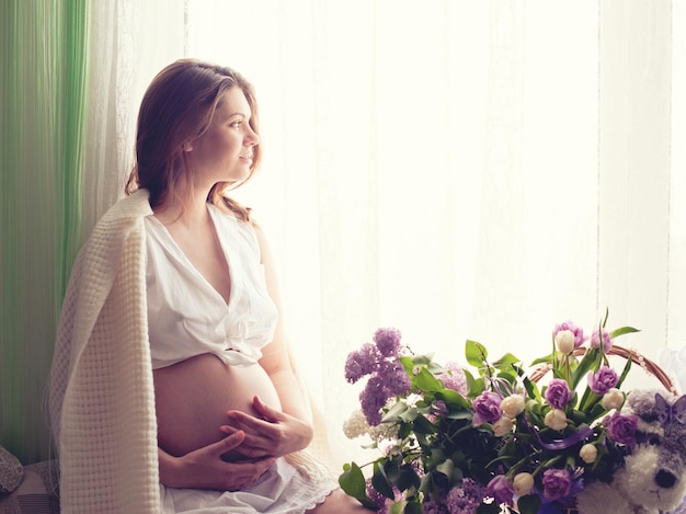 Beautiful pregnant woman sitting near window