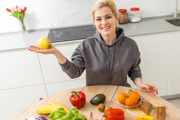 Красивая беременная женщина улыбается овощами здоровой пищи на кухне. Концепция здорового питания.