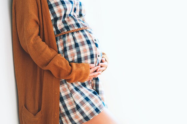 白い背景の上の手で彼女の腹に触れる美しい妊婦