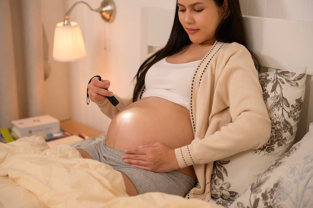 Beautiful pregnant woman using flashlight on belly to stimulate a babys development