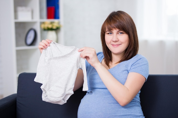 Beautiful pregnant woman with baby's clothes