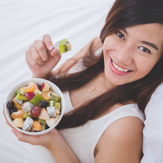 Bella donna incinta con una ciotola di frutta